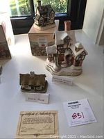 Photo of three David Winter collectible hand painted miniature houses displayed with labels and certificate of authenticity.