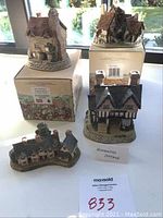 Photo showing all four David Winter miniature cottages on table with two original boxes, well lit with background window showing natural light.