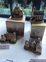 Four David Winter Collection handmade painted cottage miniatures displayed with their original boxes. Each cottage is finely detailed showing architectural features and texturing.