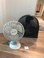 Front view of both fans, showing the white Duracraft tabletop fan next to the larger black Honeywell floor fan.