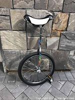 Front view of Norco unicycle showing black and white seat, chrome frame with Norco branding and black tire on paved background.