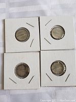 Four 1967 Canadian silver dimes in white cardboard coin holders showing front side with fish design.