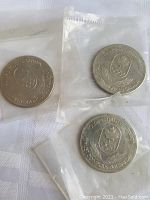 Three vintage Canadian Olympic coins individually sealed in clear plastic sleeves, showing front side with Olympic emblem and text