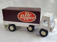 Side angle view of the toy truck showing the Dr Pepper branded maroon cargo box and white cab with black tires.