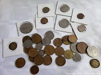 Photo shows a spread of various world coins with some in cardboard holders, predominantly Danish 5 Øre coins, a Canadian 50-cent coin, and other coins of different sizes and colors.