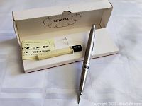 Mechanical pencil displayed alongside its original white box with Newman branding and a paper insert inside the box.