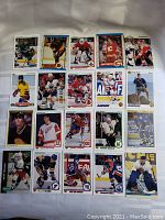 Photo showing 20 vintage rookie hockey cards arranged in rows on a white surface. Cards feature players in various team uniforms with clear text indicating rookie status.
