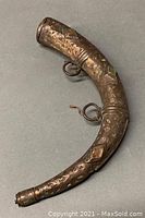 Full view of curved decorated powder horn with attached metal rings and jewel inlays.