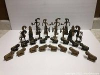 Overview of all 24 metal miniature figurines including human figures and animals arranged in rows.