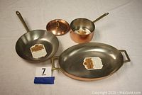 Group shot showing saucepan with lid, frying pan, and oval serving tray.