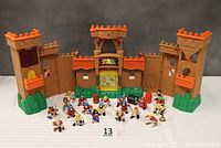 Front view of Fisher Price Eagle Talon Castle playset with multiple action figures displayed in front of it.