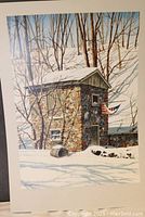 Print of a stone building in winter landscape with snow and bare trees featuring two flags, one American and one blue with a white symbol, hanging on the building