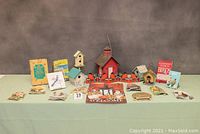 Full overview of the lot laid out on table including birdhouses, bird feeder, books, paper birds and flag