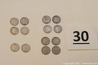 Top-down view showing all 14 Liberty Head nickels laid out in two clusters next to a sign with the number 30.