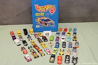 Close-up of assorted Hot Wheels die-cast cars spread out in front of the carrying case