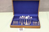 Wooden box open showing flatware arranged inside with blue cloth lining