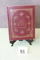 Front cover of The Holy Bible with burgundy leather-like cover and gold decorative embossing titled 'The Holy Bible'.