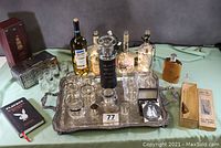 Photo showing the full bartenders delight lot on the ornate silver tray with bottles, shot glasses, flask, coasters, and books.
