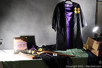 Full lot including one wizard cape displayed on hanger, second cape lying flat, Nimbus 2000 broom, wand in box, and trivia game box arranged on table.