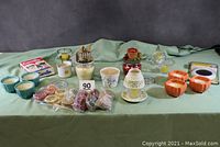 Full lot displayed on green cloth showing all candle-related items including votives, toppers, jar candles, electric warmer, and scented tarts.