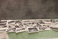Wide view of many black and white vintage railroad photographs spread out on a table, showing variety of scenes.