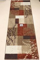 Runner rug with mixed warm tones and botanical elements, showing some wear and spots