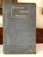 Front cover of the antique book showing title 'Universal Classic Manuscripts' in gold embossed lettering on dark grey cloth cover with visible wear and stains.