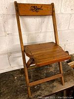 Full view of the vintage wood folding chair showing seat, legs and backrest with logo.