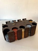 Top angled view of the antique solid wood poker chip holder with stacks of clay poker chips in multiple colors inside the carved slots.