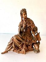 Full view of the reclining female figure sculpture showing detailed clothing and base.