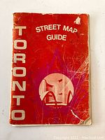 Front cover of the vintage Toronto street map guide booklet showing wear, text and circular photo of Toronto City Hall.