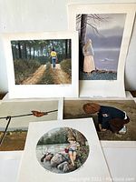 Group shot of five M. Febbo limited edition art prints showing children in natural outdoor scenes, including fishing, walking a tiger cub, and water's edge.
