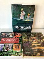 Three coffee table books of Impressionist art with colorful covers featuring Impressionist paintings. Two books are hardcover and one is softcover.