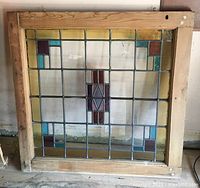 Full view of the stained glass window panel showing the wooden frame and all colored glass segments.