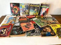 Full lot of 16 vintage 1969 and 1970 science fiction paperback books and magazines laid out on a surface showing colorful sci-fi cover art.
