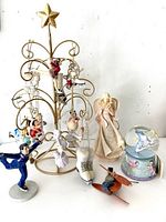 Photo of lot showing display rack with star topper and various hanging Disney figurines, ice skate ornaments, angel figurine, music snow globe, and wooden bird figurine