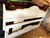 Photo showing headboard with curved top edge painted off-white.