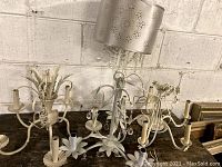 Four white ceiling light fixtures, two chandeliers and two drum-shaped fixtures with floral cut-outs and crystal strands