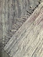 Close-up of the woven texture and fringed edge of the vintage rag rug showing variegated colours and fabric weave.