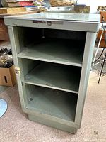 Side and front view showing open shelves and green paint with some scratches.