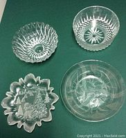 Four glass and crystal bowls on green fabric background, clearly showing distinct patterns and shapes of each bowl