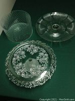 Three glass serving items including a Walther glass cake stand with floral design base, Arcoroc cake stand with petal design, and glass trifle bowl with swirled pattern
