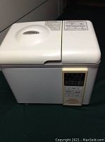 White Home Bakery bread maker with top lid and control panel on front side.