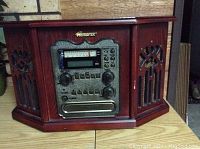 Front view of the Memorex audio console showing controls, radio tuner, cassette slot, and decorative wooden cabinet with carved side panels.