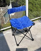 Blue folding camp chair with metal frame and fabric seat and backrest, shown unfolded.