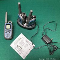 Three Uniden radios with dual charging base, power adapter, and user manual on green background.