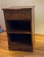 Photo of small dark wood side table showing front with two drawers and two shelves.