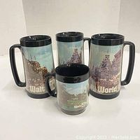 Front view of four Thermo-Serv mugs with Walt Disney World print, three large and one small.