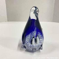 Front view of blue and clear glass penguin paperweight with visible internal penguin scene.