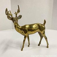 Full side view of the brass stag deer figurine showing overall shape and polished brass surface.